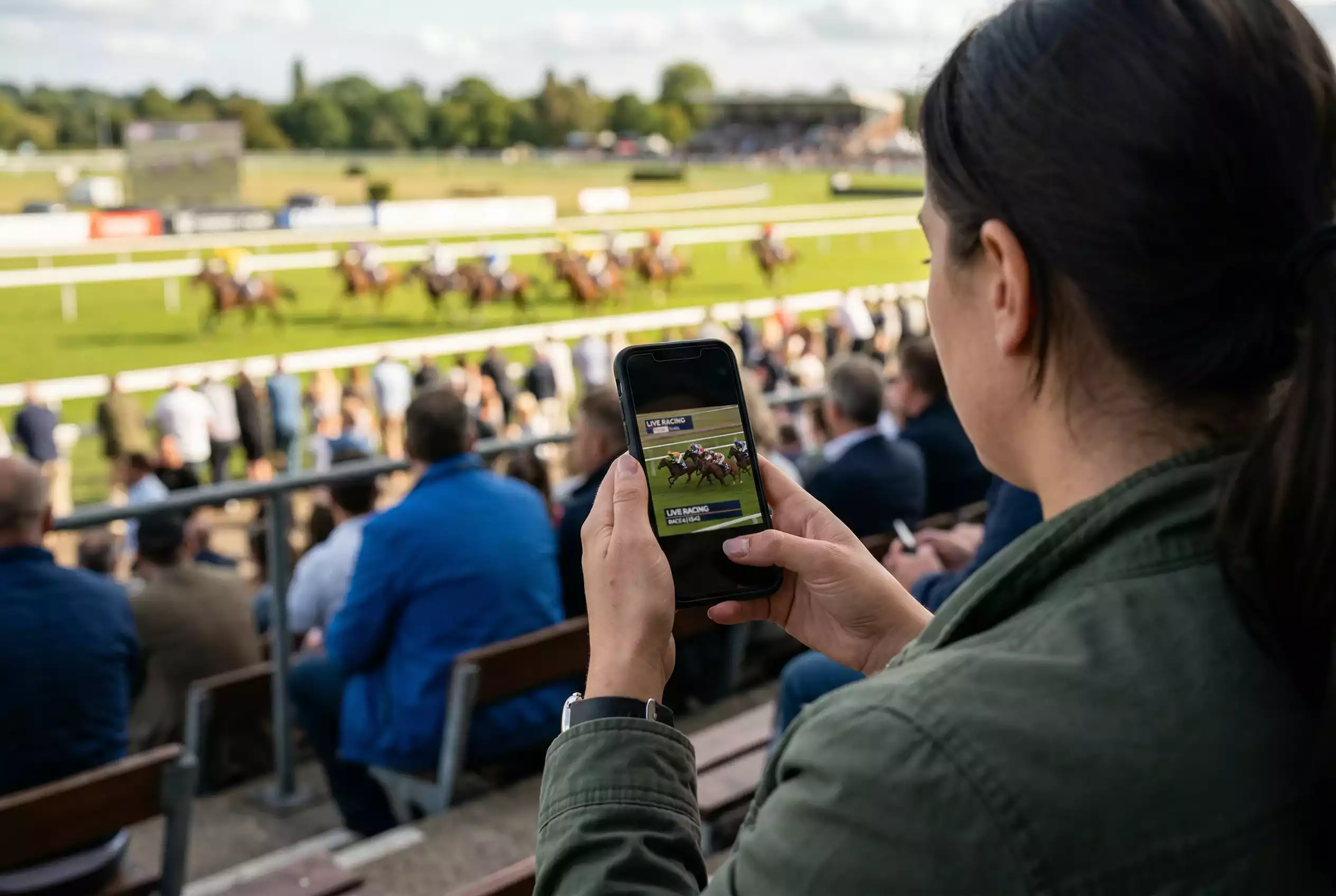 Pessoa usando telemóvel para acompanhar corrida de cavalos ao vivo em plataforma de apostas